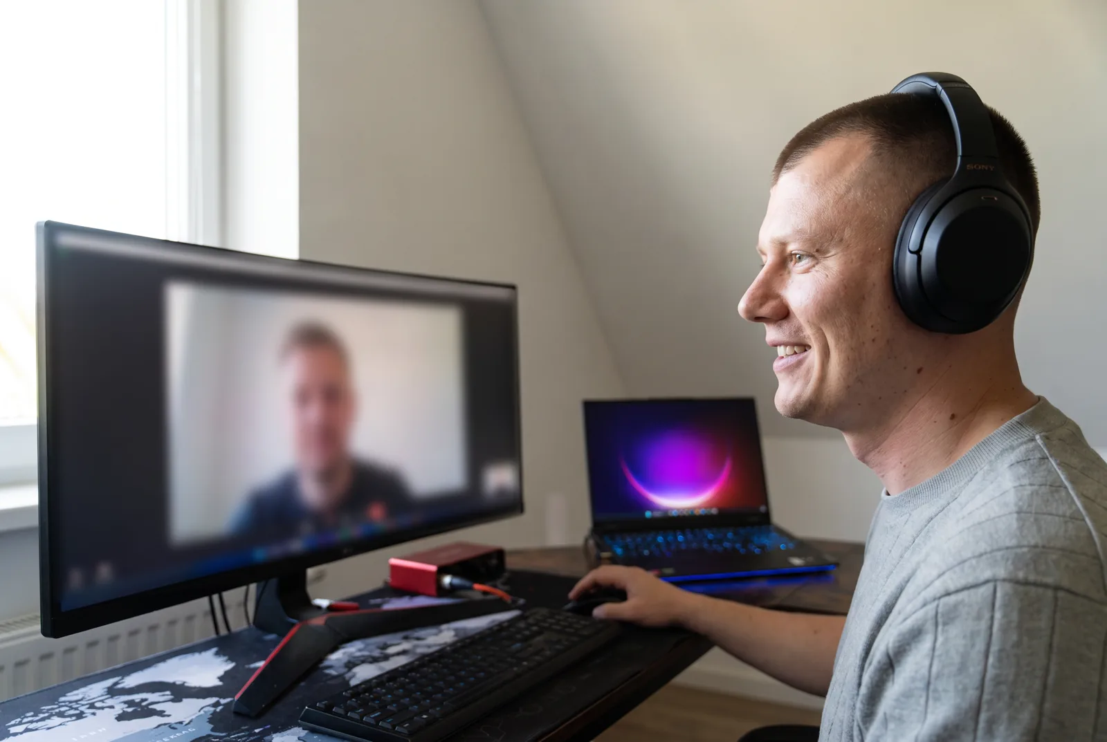 Adrian on a video call at his desk, headphones on
